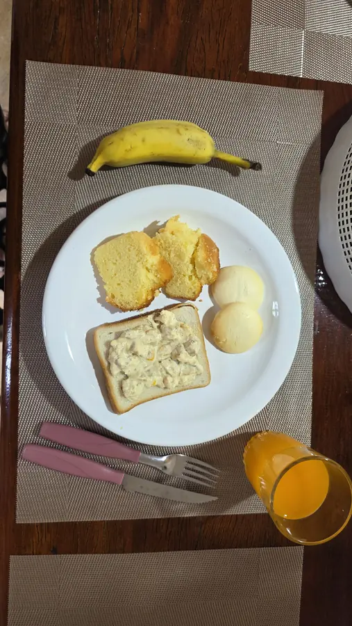 Prato de café da manhã com pão, ovos, banana e suco