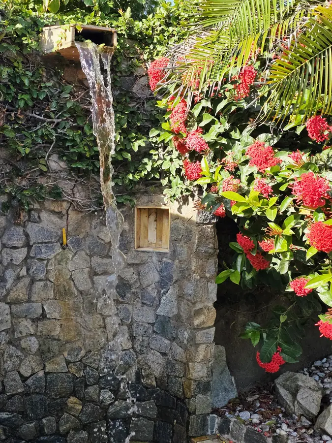 Ducha externa entre pedras e flores